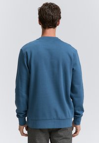 Felpa blu con maniche lunghe e scollo tondo. Realizzata in tessuto morbido, presenta polsini e orlo a costine. Design semplice e classico.