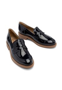Black patent leather loafers with a decorative bow detail, round toe, and a contrasting brown rubber sole. Smooth texture and polished finish.