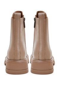 Botas de tobillo de cuero beige con una textura suave, cierre de cremallera y una suela resistente, con costuras mínimas y punta redondeada.