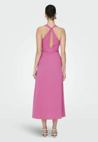 Roza maksi obleka s halter vratom, ki ima zasnovo z odprtinami na hrbtu, gladko teksturo in lepe linije. Nosijo se z zlatimi petami.