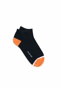 Schwarze Knöchelsocken mit einer orangen Zehenkappe, weißen Akzenten und dem Text "THE ACTIVE BÁS", der nahe dem Knöchel aufgedruckt ist. Glatte Stricktextur.
