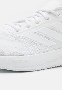 Sneaker atletica bianca con tomaia in rete, caratterizzata da tre strisce bianche, superficie testurizzata e marchio "CLOUDfoam" sulla suola.