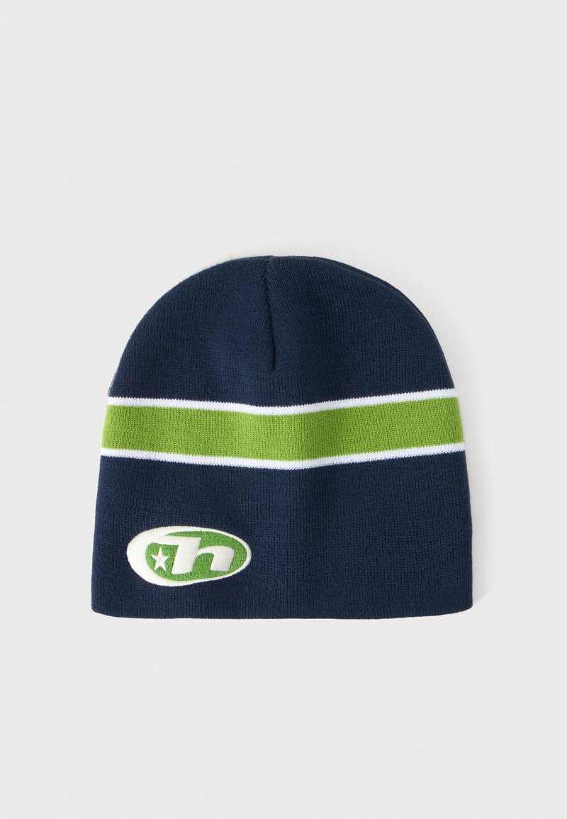 Bonnet en maille bleu marine avec une bande horizontale verte bordée de lignes blanches et un logo ovale vert et blanc comportant une étoile et la lettre "h" à l'avant.