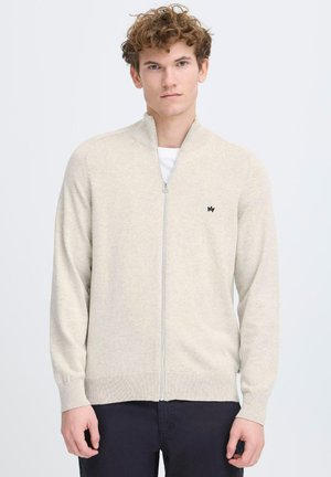 Suéter de cremallera color beige claro con un cuello alto, puños y dobladillo acanalados, que presenta un pequeño logo negro en el pecho. Textura suave y de punto.