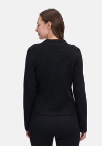 Svart långärmad cardigan med en slät textur, prydd med en krage och en figursydd midja. Diskret lyster ger en antydan av elegans.