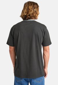 Dark gray t-shirt with short sleeves, featuring a patterned neckline. Material is soft cotton, cut in a relaxed fit.