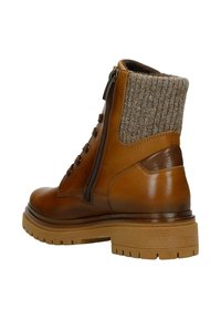 Brązowy skórzany botek za kostkę z dzianinową, szarą, elastyczną mankietem, bocznym zamkiem błyskawicznym i gumową podeszwą, wyposażony w sznurowanie i wzmocnioną piętę.