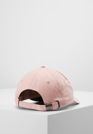 Casquette de baseball en coton rose clair avec sangle ajustable et boucle en métal, reposant sur une surface blanche sur un fond uni.