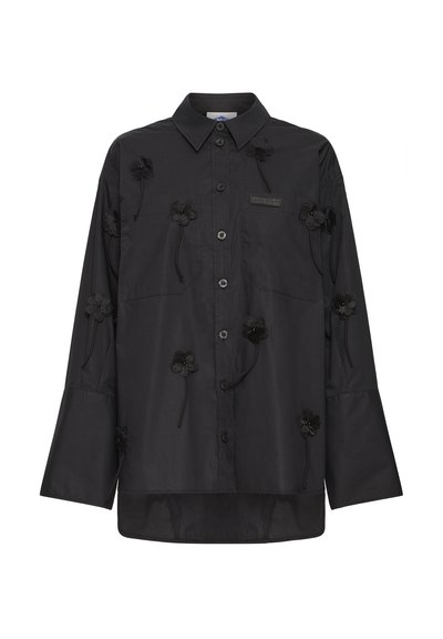 Sort langærmet skjorte med knapper og spidst krave, dekoreret med små sorte blomsterapplikationer spredt på fronten og ærmerne.