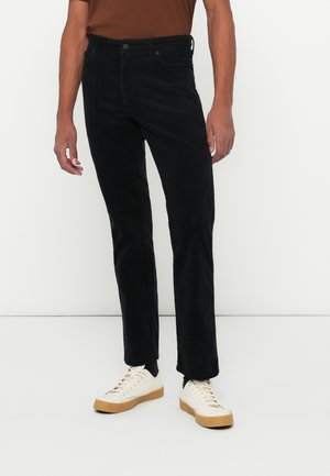Black corduroy pants with a straight fit, featuring a button closure, belt loops, and side pockets, paired with white sneakers.