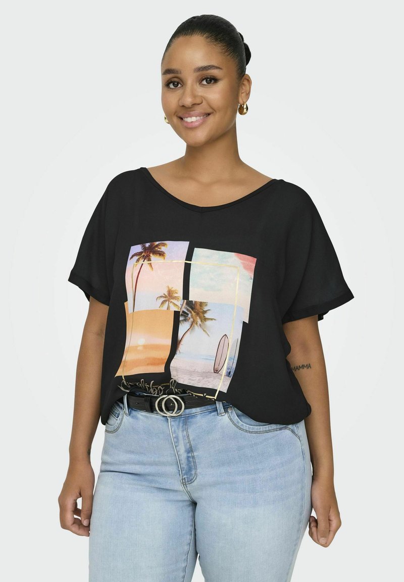 Camisa negra de manga corta con un gráfico colorido de una escena de playa con palmeras, combinada con unos vaqueros de mezclilla azul claro y un cinturón negro.