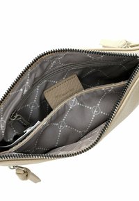 Interno di una borsa in pelle beige con una tasca con zip, fodera grigia con un motivo geometrico e una tasca per portacarte testurizzata.
