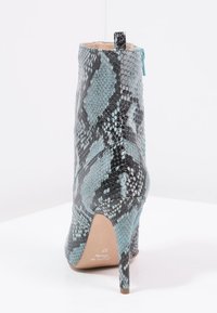 Ormskinnsankl boot, med en glänsande textur i blått och svart, hög stilettklack och dragkedja bak.