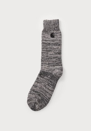 Calcetín de punto gris y negro con puño acanalado, que presenta un pequeño logo negro en el costado. Tejido texturizado con un patrón mezclado.