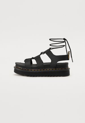Black platform sandals with multiple straps, lace-up design, textured rubber sole, and contrasting stitching along the edge.