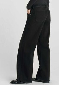 Zwarte wijde jeans met een hoge taille, gemaakt van denim. Heeft uitgebreide stiksels op de achterzakken en een gladde textuur.