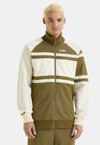Giacca zip-up verde oliva e bianca con colletto alto, caratterizzata da righe orizzontali, tasche laterali, polsini a coste e logo sul petto.