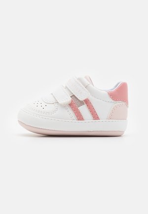 Bottines pour bébé blanches et roses avec doubles sangles Velcro, bout perforé et détails cousus sur un fond blanc uni.