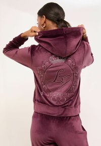 Sametová mikina v hlbokej purpurovej farbe s dekoratívnym dizajnom zo rhinestone na chrbte, vrátane koruny a nápisu "LIPSY" na banneri.