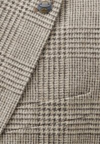 Brown and cream houndstooth-patterned jacket fabric with a textured weave, featuring a single button and a front pocket.