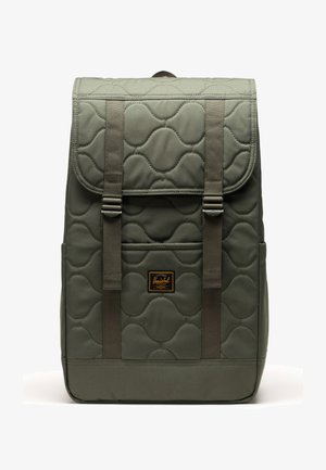 Gequiltede olijfgroene rugzak met twee verstelbare banden, een voorzak en een bruine label. Heeft een soepele textuur en ronde patronen.