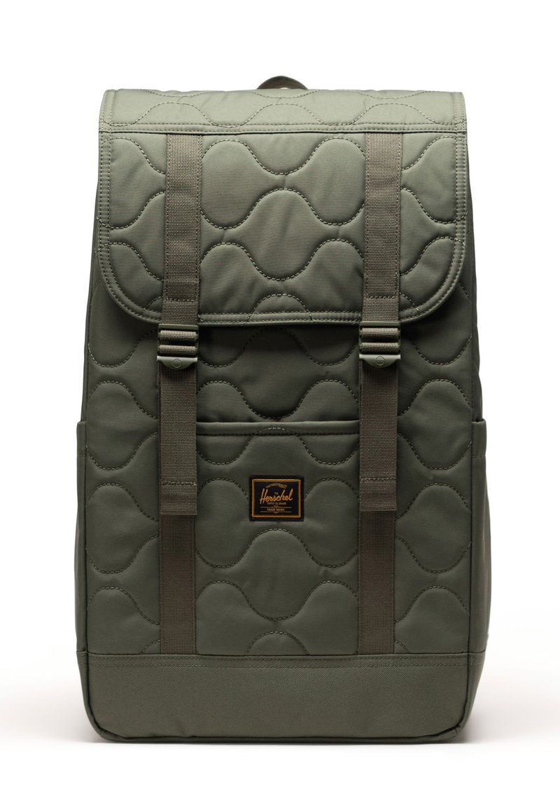 Gepolsterter olivgrüner Rucksack mit zwei verstellbaren Trägern, einer Vordertasche und einem braunen Etikett. Er hat eine glatte Textur und abgerundete Muster.