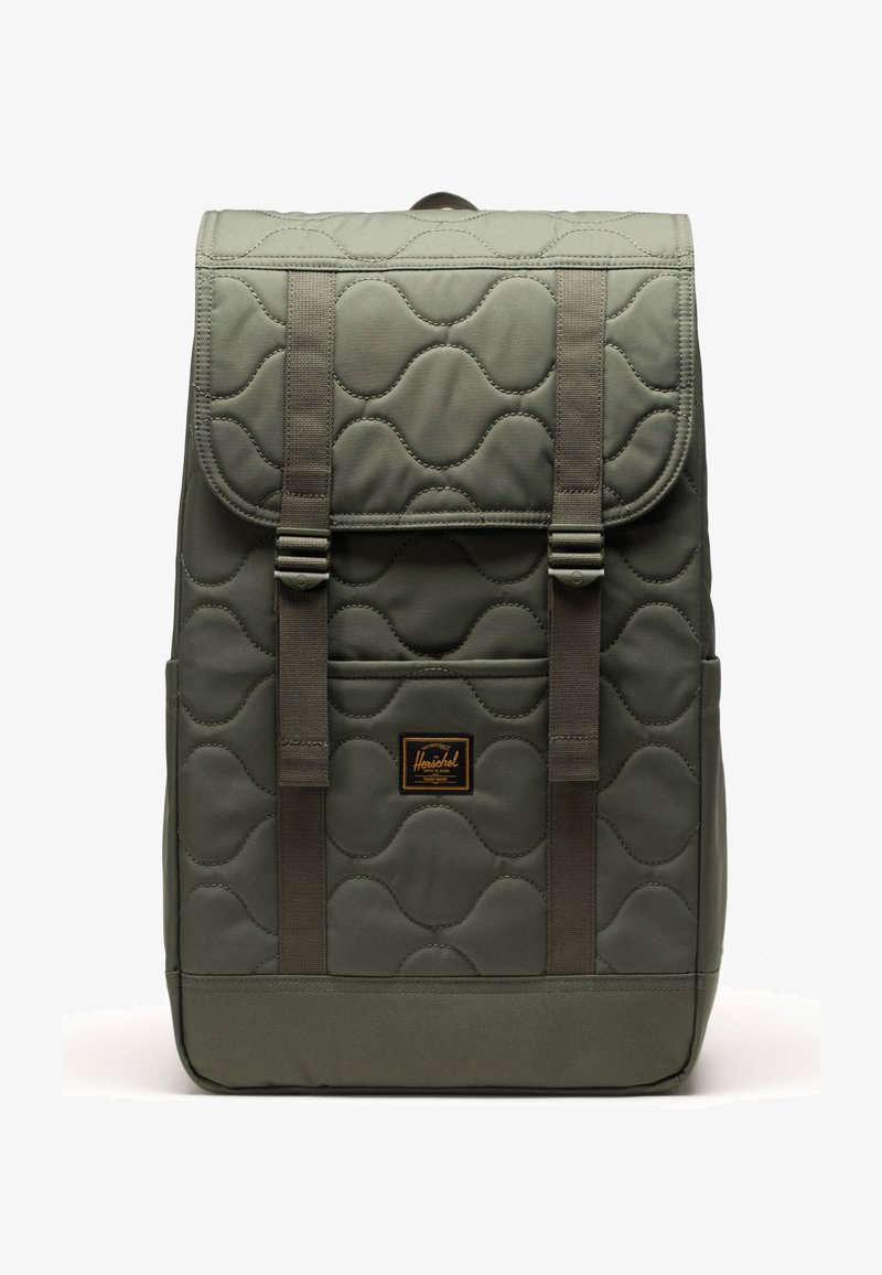 Gepolsterter olivgrüner Rucksack mit zwei verstellbaren Trägern, einer Vordertasche und einem braunen Etikett. Er hat eine glatte Textur und abgerundete Muster.