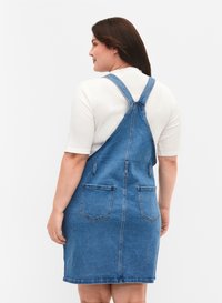 Sinikaopuku denim sinisenä, ilman hihoja suoralla leikkauksella, jossa on kaksi takataskua ja säädettävät hihnat. Sujuva pinta.