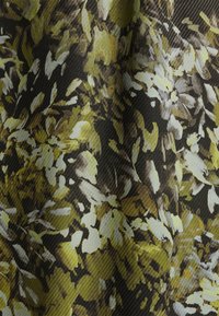 Tissu à motifs floraux avec des nuances de vert et de crème sur un fond sombre ; présente une surface texturée avec un léger relief.