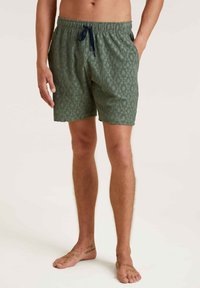 Groene zwembroek met patroon, elastische tailleband en trekkoord. Voorzien van twee zijzakken en een gestructureerde stof.