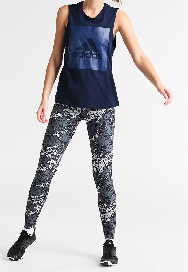 Merihenkinen hihaton paita, jossa on kiiltävä Adidas-logo, sekä mustavalkoiset leggingsit, joissa on tekstuurinen digitaalinen camokuvio.