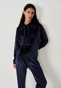 Granatowy dres velurowy z długim rękawem, z kapturem i sznurkami, oraz pasującymi spodniami o gładkiej, miękkiej teksturze.