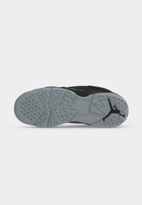 Semelle de chaussure grise avec des motifs géométriques et des crampons circulaires, avec un logo Jumpman noir près du talon.