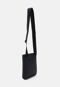 Borsa a tracolla nera con una texture liscia, forma rettangolare e tracolla regolabile. Presenta una tasca a soffietto sulla parte frontale per ulteriore spazio di stoccaggio.