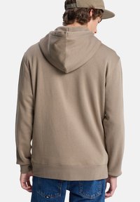 Capuchon sweatshirt in beige, gemaakt van zacht materiaal, met een relaxte pasvorm, ribgebreide boorden en een klein label aan de achterkant.