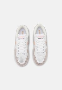 Bílé tenisky s růžovými a béžovými akcenty. Hladká kůže a semišové textury, perforovaná špička a šněrovací design s logem na jazyku.