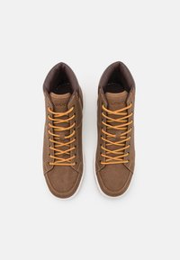 Zapatillas altas marrones con una superficie texturizada, cordones naranjas y suelas de goma blanca, que cuentan con un cuello acolchado para mayor comodidad.