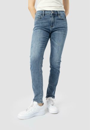 Úzké džíny ve světle modrém denimu, s klasickým designem pěti kapes a jemným odřením. V kombinaci s bílými teniskami.