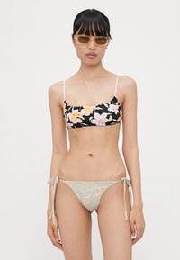 Cvetni bikinij set featuring črno zgornji del z rumenimi in roza cvetovi ter svetlo zelenim spodnjim delom s podobnimi motivi, nastavljive stranice.
