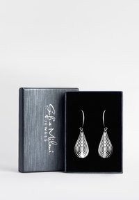 Silvriga droppörhängen med lagerdesign och en glänsande yta. Visas i en svart smyckeslåda med strukturerad yta.