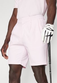 Ljusrosa golfshorts med veck, bälteshällor och en skräddarsydd passform. Tillverkade av lättviktsmaterial, med sidofickor och subtil textur.