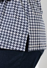 Kurzarmhemd im marineblauen und weißen Hahnentritt-Muster, mit seitlichen Schlitzen, aus leichtem Baumwollstoff gefertigt.