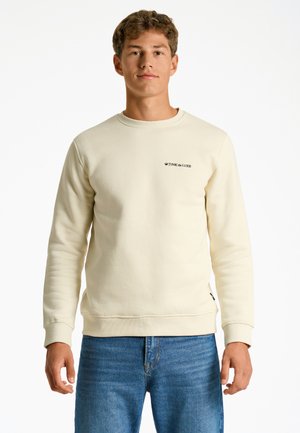 Crème sweatshirt met een ronde hals, ribgebreide cuffs en zoom. Bevat een klein zwart 'JUNK de LUXE' logo op de linkerborst. Combinatie met blauwe jeans.