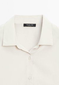 Cream button-up shirt with a soft texture, featuring a classic collar, five buttons, and a label reading "Massimo Dutti."