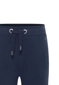 Marineblaue Sweatpants mit einer Kordelzugtaille, ausgestattet mit silbernen Ösen, seitlichen Taschen und einer weichen Textur. Flach geschnitten an den Beinöffnungen.