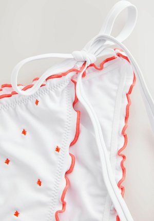 Bílý bikinový top s korálovým scalloped lemem, vyšívaný malými oranžovými akcenty, se zavazováním na zádech. Měkká textura.