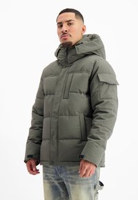 Groene gewatteerde jas met capuchon, voorzien van een ritsluiting, zijzakken en een utiliteitszak op de mouw. Glad textuur, casual ontwerp.