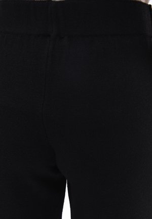 Black leggings made of soft, stretchable fabric with a smooth texture and elastic waistband, featuring a simple, form-fitting design.