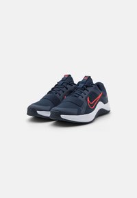 Navy blue urheilujalkineet, joissa on muotoiltu verkko-osa, valkoinen pohja ja oranssi swoosh-korostus. Kengissä on nauhat ja pehmustettu kieli mukavuutta varten.