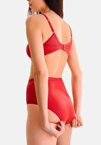 Rood lingerie set met een getextureerde beha met verstelbare bandjes en een hoog- taille onderbroek, die een soepele, aansluitende silhoutte laat zien.
